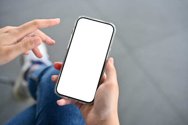Una mano femenina sosteniendo una maqueta de teléfono inteligente sobre la vista superior de fondo borroso
