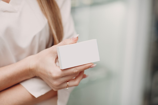 Mano femenina sosteniendo el paquete de caja en blanco blanco