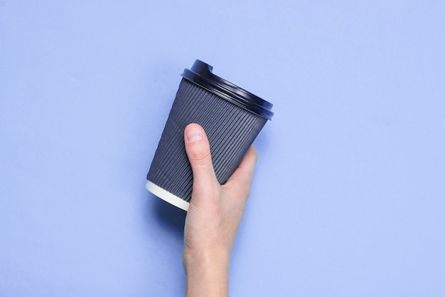 Mano femenina sosteniendo la taza de café de papel rojo aislado