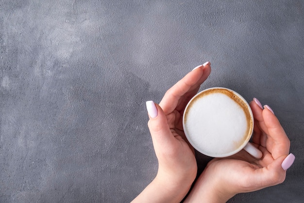 Mano femenina sosteniendo una taza de café.