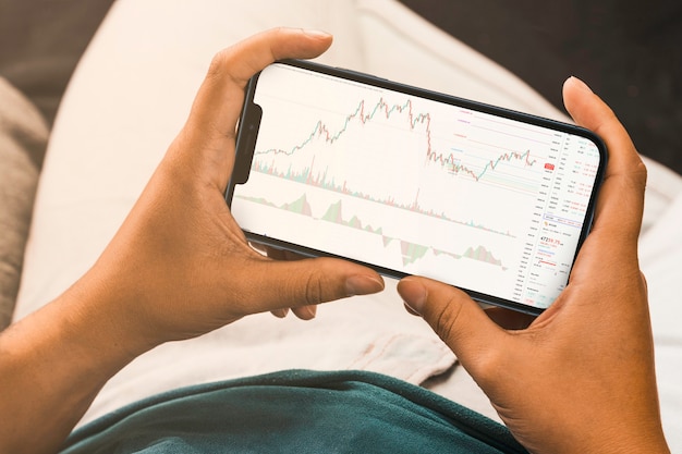 Mano femenina sosteniendo un teléfono inteligente con gráfico de mercado de valores financieros en la pantalla. Bolsa. Río de Janeiro, RJ, Brasil. Septiembre de 2021.