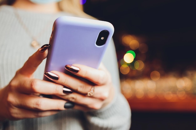 Mano femenina sosteniendo un teléfono morado en una funda de silicona transparente aislada