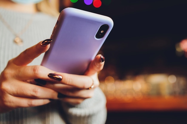 Mano femenina sosteniendo un teléfono morado en una funda de silicona transparente aislada