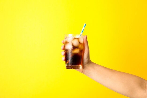 Mano femenina sosteniendo un vaso con hielo cola y túbulo