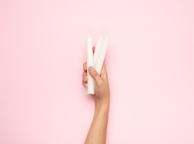 Mano femenina sosteniendo una vela de cera blanca