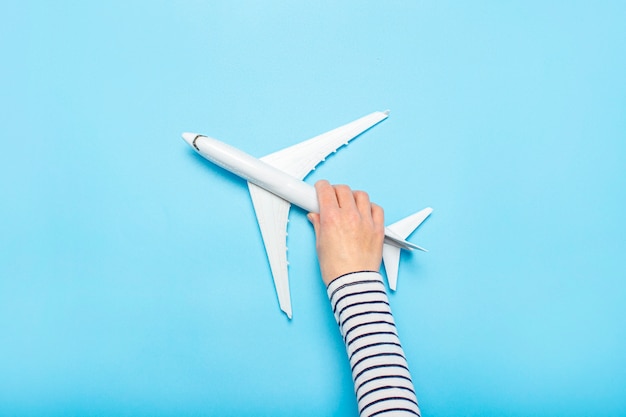 Mano femenina sostiene un avión en un espacio azul. Concepto de vuelo, billetes, reserva, búsqueda de vuelos, viajes