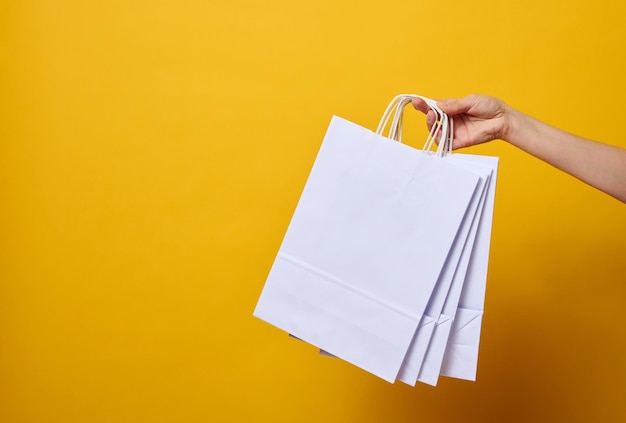 Mano femenina sostiene una bolsa de papel desechable con asas para alimentos y ropa. Envases reciclables. Cero desperdicio