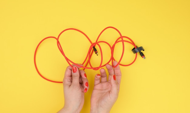 La mano femenina sostiene el cable trenzado para cargar dispositivos móviles