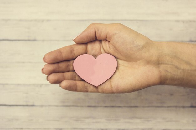 Una mano femenina sostiene un corazón de madera, el concepto de amor.