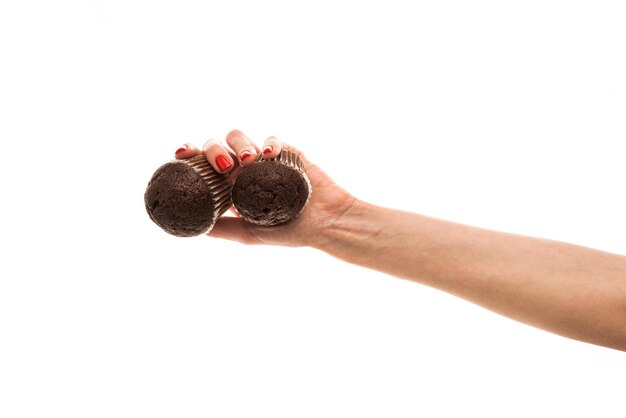 Mano femenina sostiene un cupcake de chocolate marrón aislado sobre fondo blanco.