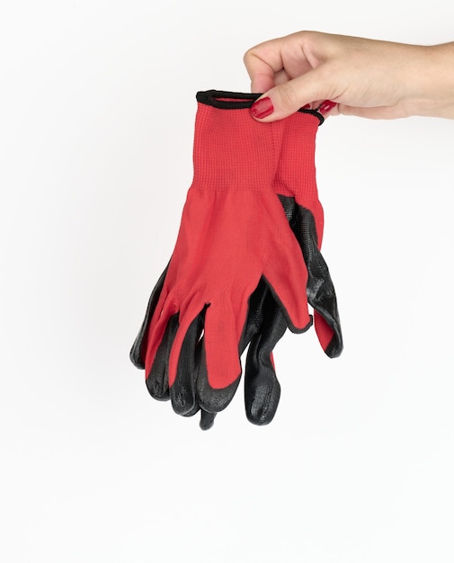 Foto mano femenina sostiene guantes de trabajo textiles rojos sobre un fondo blanco. ropa protectora para trabajadores manuales, cerrar