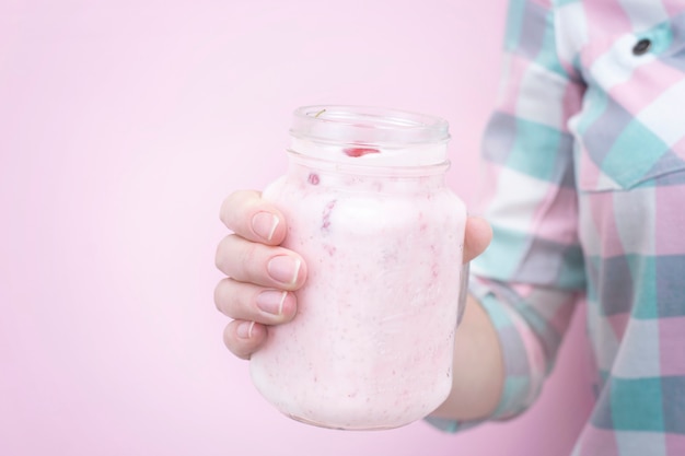 Mano femenina sostiene un primer batido de leche con bayas