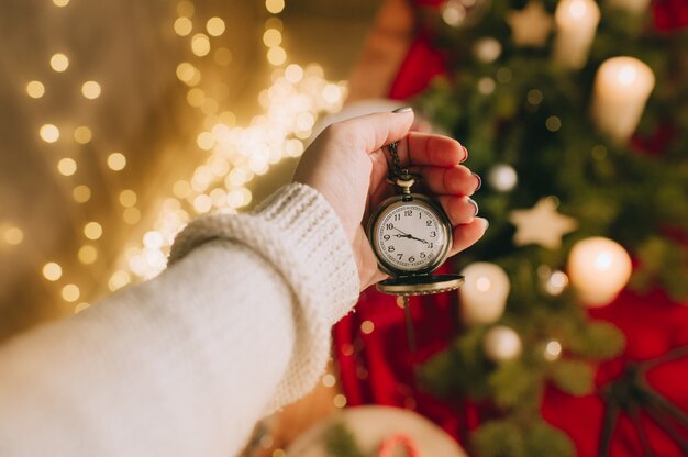 Mano femenina sostiene reloj en superficie de luces borrosas