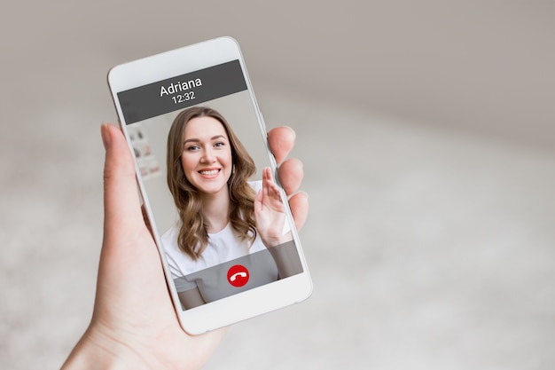 Foto una mano femenina sostiene un teléfono móvil con una niña en la pantalla, chat de video. una mujer le hace una videollamada a su amiga. feliz niña sonríe en una pantalla de teléfono, interfaz, botones de llamada