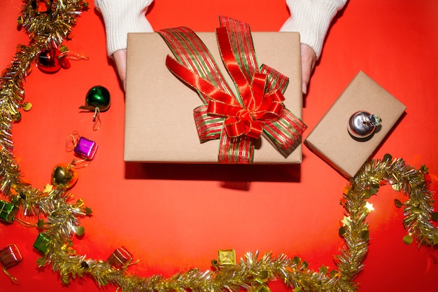 mano femenina en suéter sosteniendo una caja roja presente para Navidad