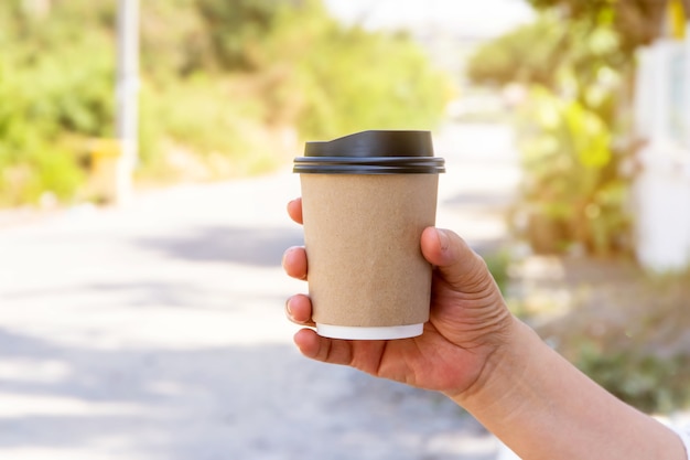 Mano femenina con taza de café de papel para llevar, tazas de café de papel en manos de mujeres con manicura perfecta