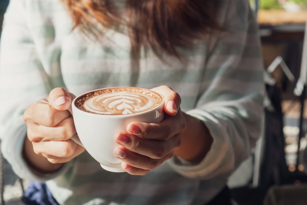 Mano femenina taza de chocolate caliente o chocolate en la mesa de madera, de cerca