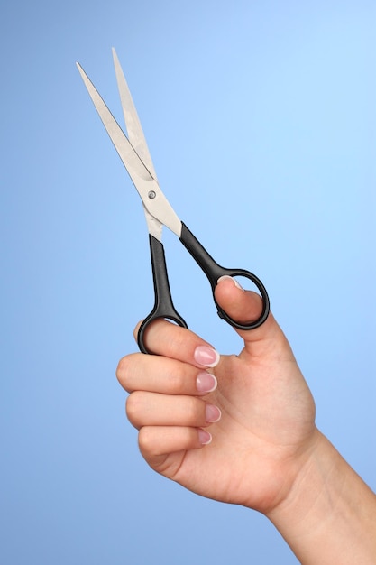 Mano femenina con tijeras sobre fondo de color