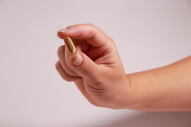 mano femenina tomando cápsulas de Omega 3 de aceite de pescado