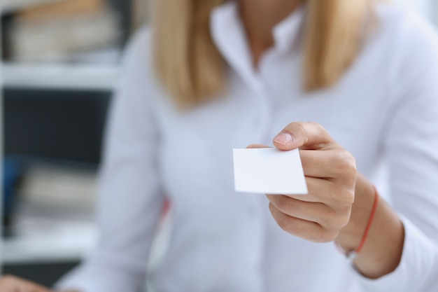 Mano femenina en traje dar tarjeta de visita en blanco al visitante masculino