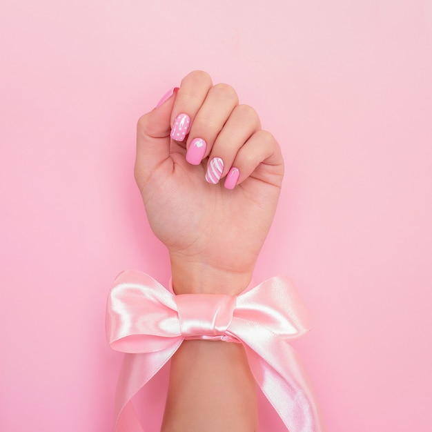 Mano femenina con uñas de manicura románticas, diseño de corazón