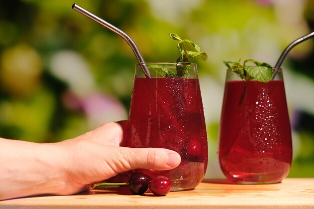 Mano femenina con vaso de jugo de cereza