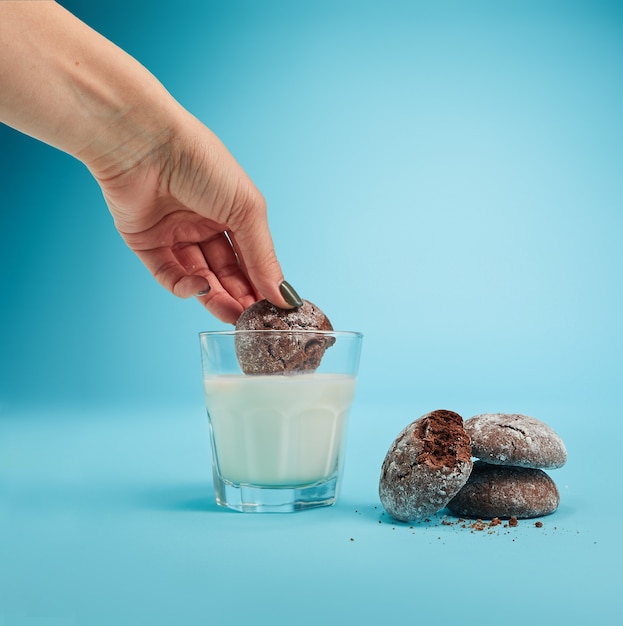 La mano femenina y vaso de leche y galletas de avena