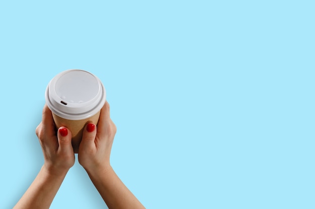 Mano femenina con vaso de papel aislado en azul