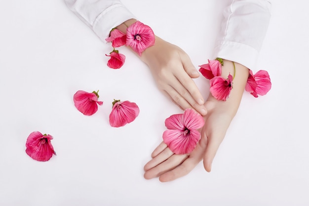 La mano y la flor del color de la primavera están en el cuidado de la piel de la mesa.