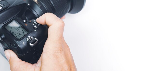 Mano del fotógrafo a punto de hacer clic en el botón del obturador de la cámara digital DSLR con un espacio de copia y un fondo blanco