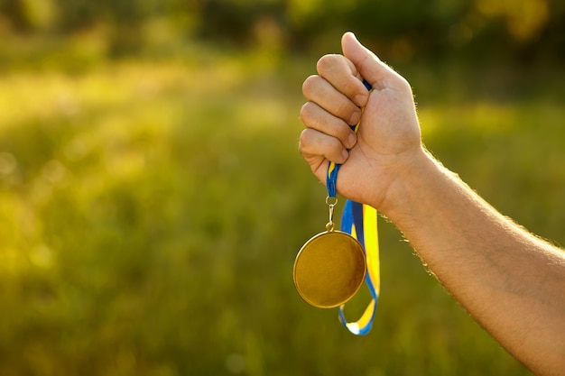 Mano ganadora con medalla de oro con cinta