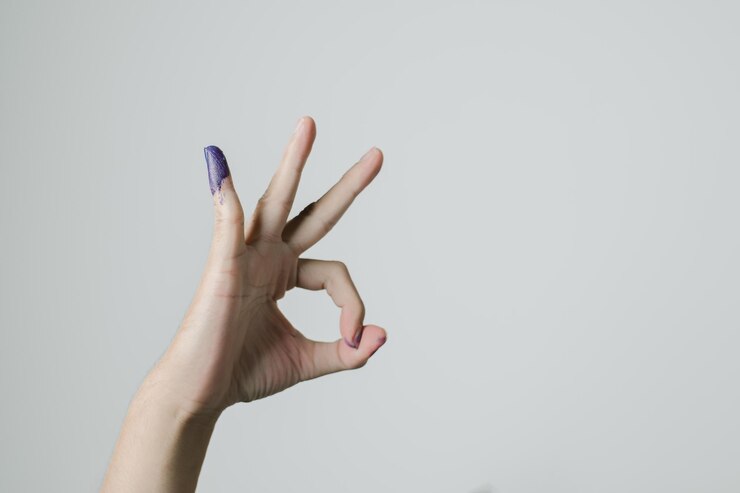 Una mano con el gesto OK y tinta púrpura aplicada en el dedo meñique después del pemilu o las elecciones presidenciales indonesias