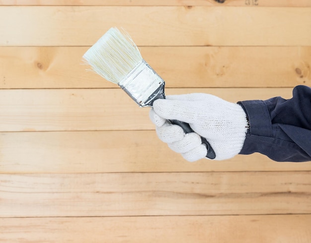 La mano en el guante de algodón sosteniendo pinturas de pincel