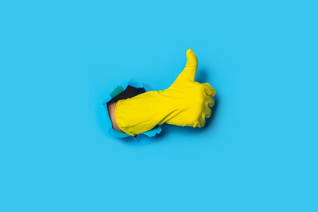 La mano en el guante amarillo muestra la clase de pulgar hacia arriba en un azul brillante