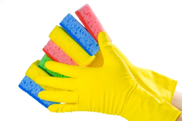 Una mano en un guante amarillo sostiene un conjunto de esponjas aisladas en un primer plano de fondo blanco
