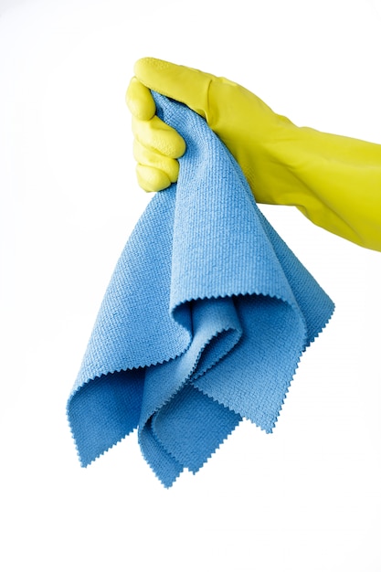 Mano en guante de goma amarillo con tela sobre fondo blanco.