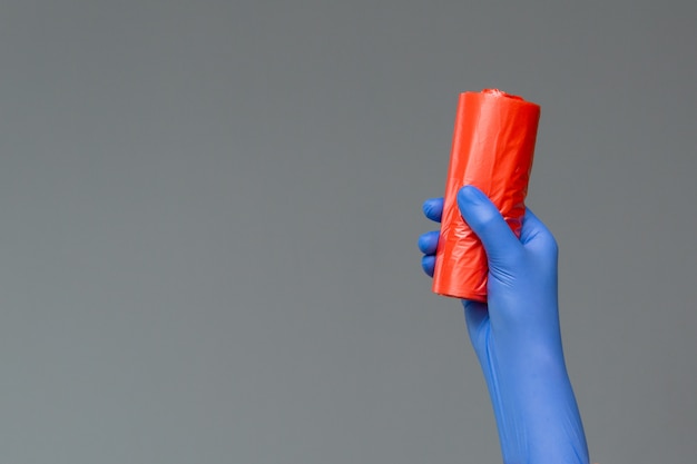 La mano en el guante de goma sostiene una bolsa de basura de colores