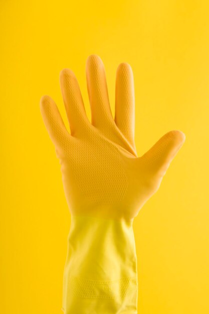 Mano en un guante de limpieza de goma amarillo