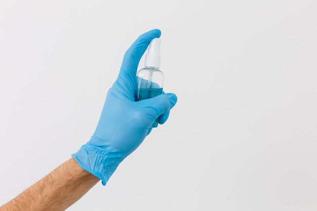 La mano en un guante médico desechable azul sostiene gel antiséptico, higiene y prevención de enfermedades, medidas antivirales, cuarentena 2020