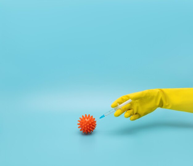 Foto una mano con un guante protector hace una inyección en un modelo de una célula de coronavirus