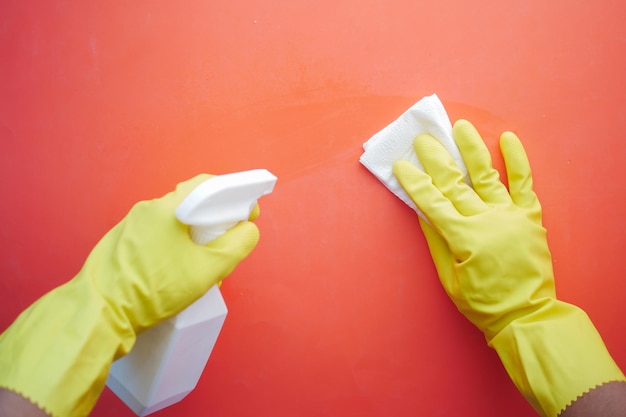 Mano en guantes de goma amarillos que sostienen la mesa de limpieza de botellas de spray