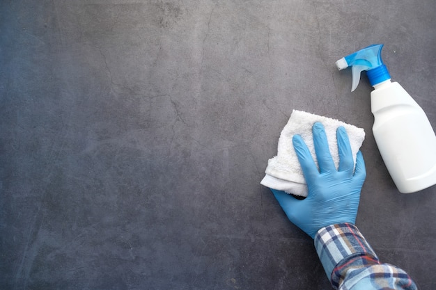 Mano en guantes de goma azul mesa de limpieza con paño