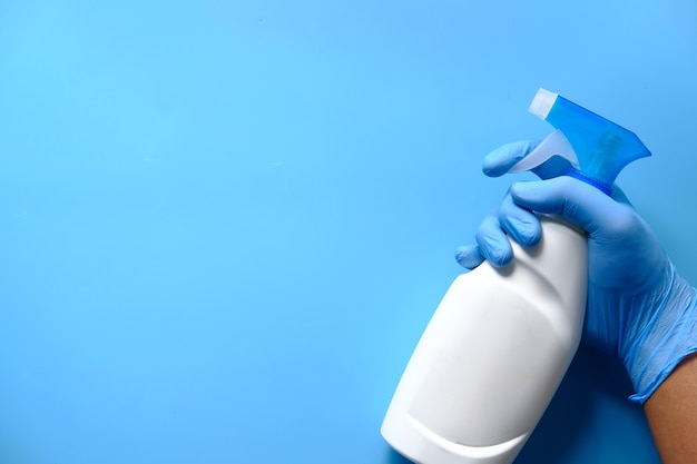 Mano en guantes de goma azul sosteniendo una botella de spray con espacio de copia, vista superior