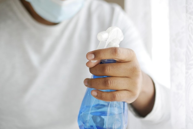 Foto mano en guantes de goma azul sosteniendo una botella de spray con espacio de copia