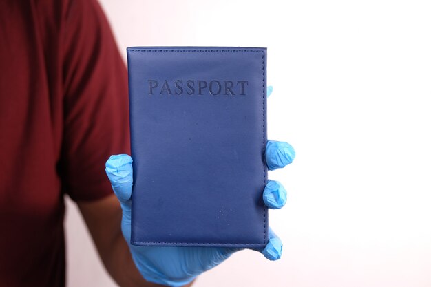 mano en guantes quirúrgicos azules con pasaporte en mano.