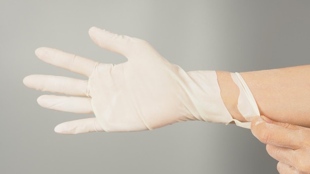 Mano con guantes rasgados blancos sobre fondo gris