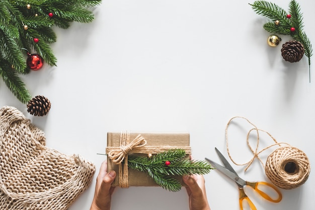 Mano haciendo caja de regalos para concepto de navidad con adornos