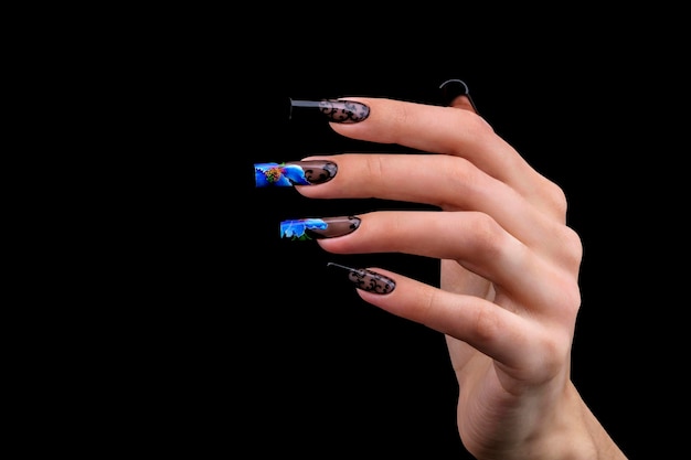 Mano con una hermosa manicura sobre un fondo negro Diseño de uñas Uñas extendidas