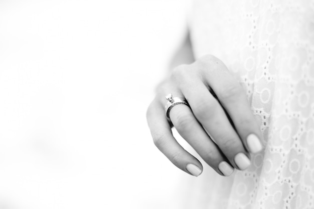 Mano hermosa de la mujer con el anillo de bodas con el fondo del océano.