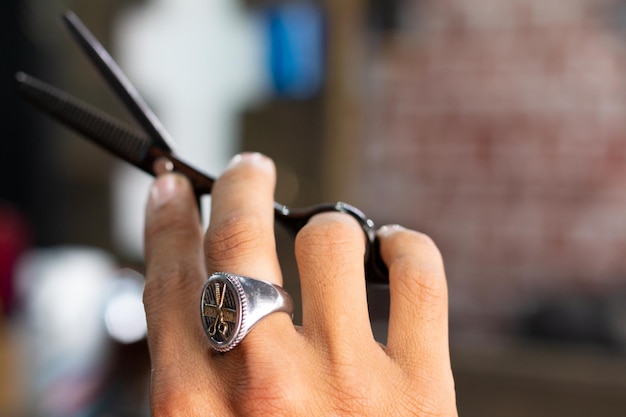 Mano con hermosas tijeras negras y un hermoso anillo estilo barbería vintage